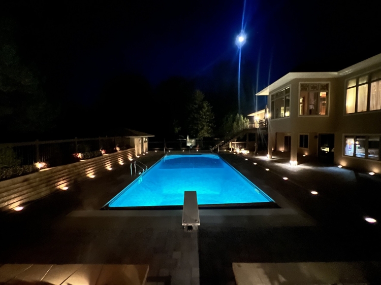 Night view of paver pool deck with lighting.