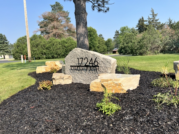 Eden stone address marker with Eden boulder outcroppings in landscape bed.