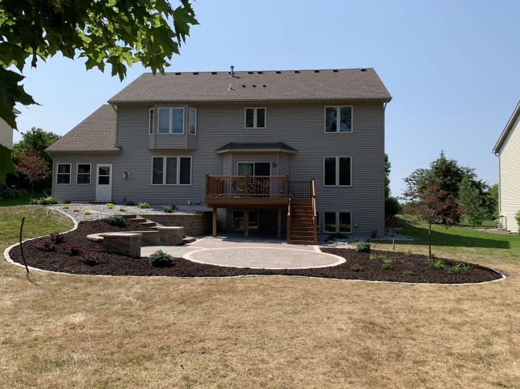 Large slab 5- piece paver patio with circle patio inlay and seating wall with pillars and block staircase.