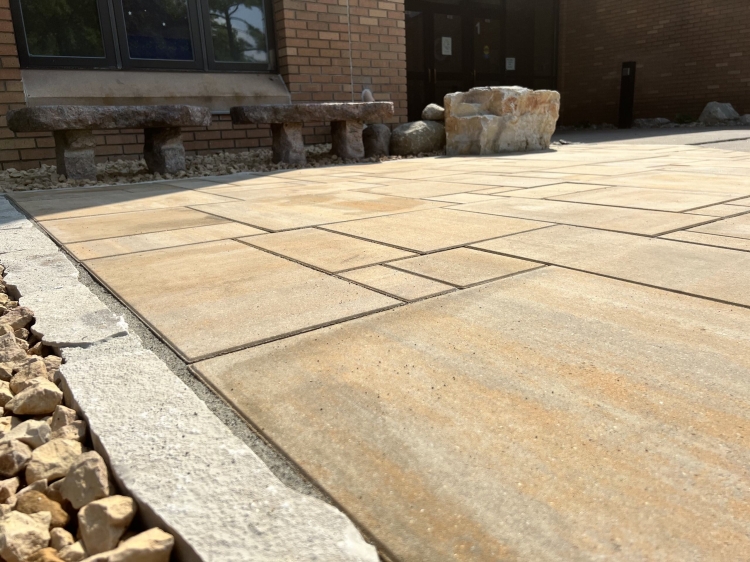 6-piece slab paver patio with Eden natural stone border. Stone benches and a seating boulder inlayed into patio edge.