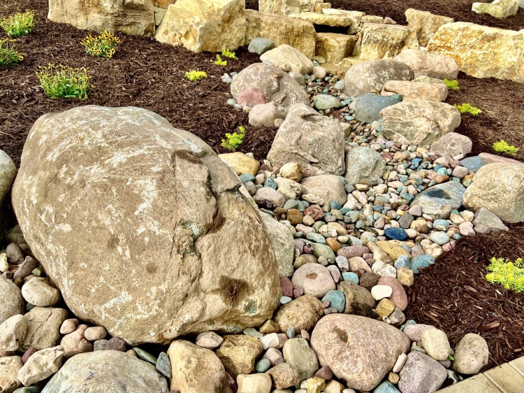 Beautiful pond-less waterfall built into limestone retaining wall with fieldstone stream dying into patio area.