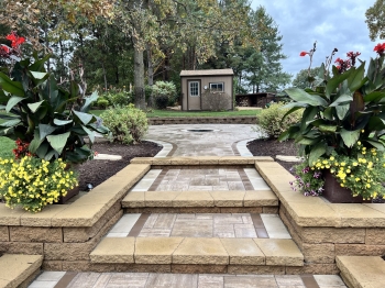 Paver walkway to leading to paver patio with recessed firepit. 