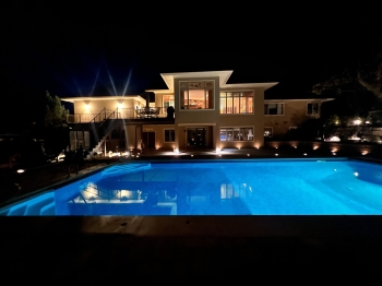 Night view of large slab paver pool deck with lighting.