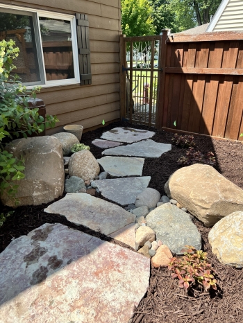 Large slab Chilton flagstone meandering in a beautiful flower garden with fieldstone boulder outcroppings.