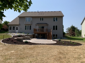 Large slab 5- piece paver patio with circle patio inlay and seating wall with pillars and block staircase.