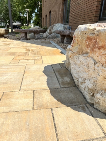 6-piece slab paver patio with Eden natural stone border. Stone benches and a seating boulder inlayed into patio edge. 