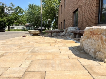 6-piece slab paver patio with Eden natural stone border. Stone benches and a seating boulder inlayed into patio edge. 