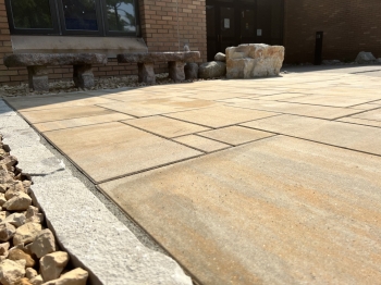 6-piece slab paver patio with Eden natural stone border. Stone benches and a seating boulder inlayed into patio edge. 