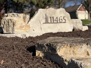 Eden stone address marker with large Eden boulder outcroppings in landscaping bed. 
