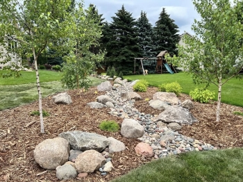 Beautiful landscape bed with a dry river bed designed to help drain water between the properties. 