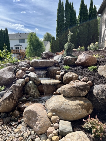 Beautiful plantings around a pond-less water feature.