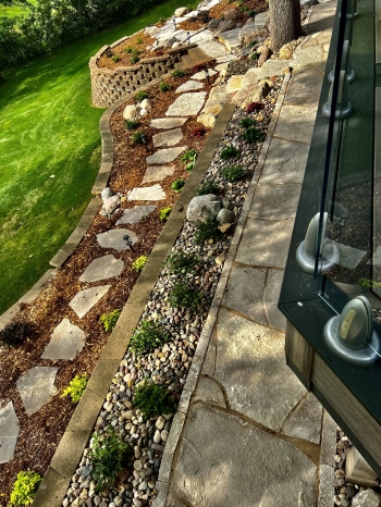 Colorful mix of perennials and shrubs along a flagstone walkway and flagstone steppers