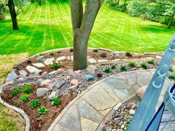 Colorful mix of perennials and shrubs along a flagstone walkway and flagstone steppers